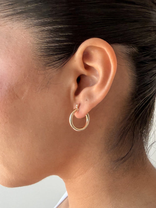 close-up of model wearing senoe classic hoop earrings in 10k yellow gold
