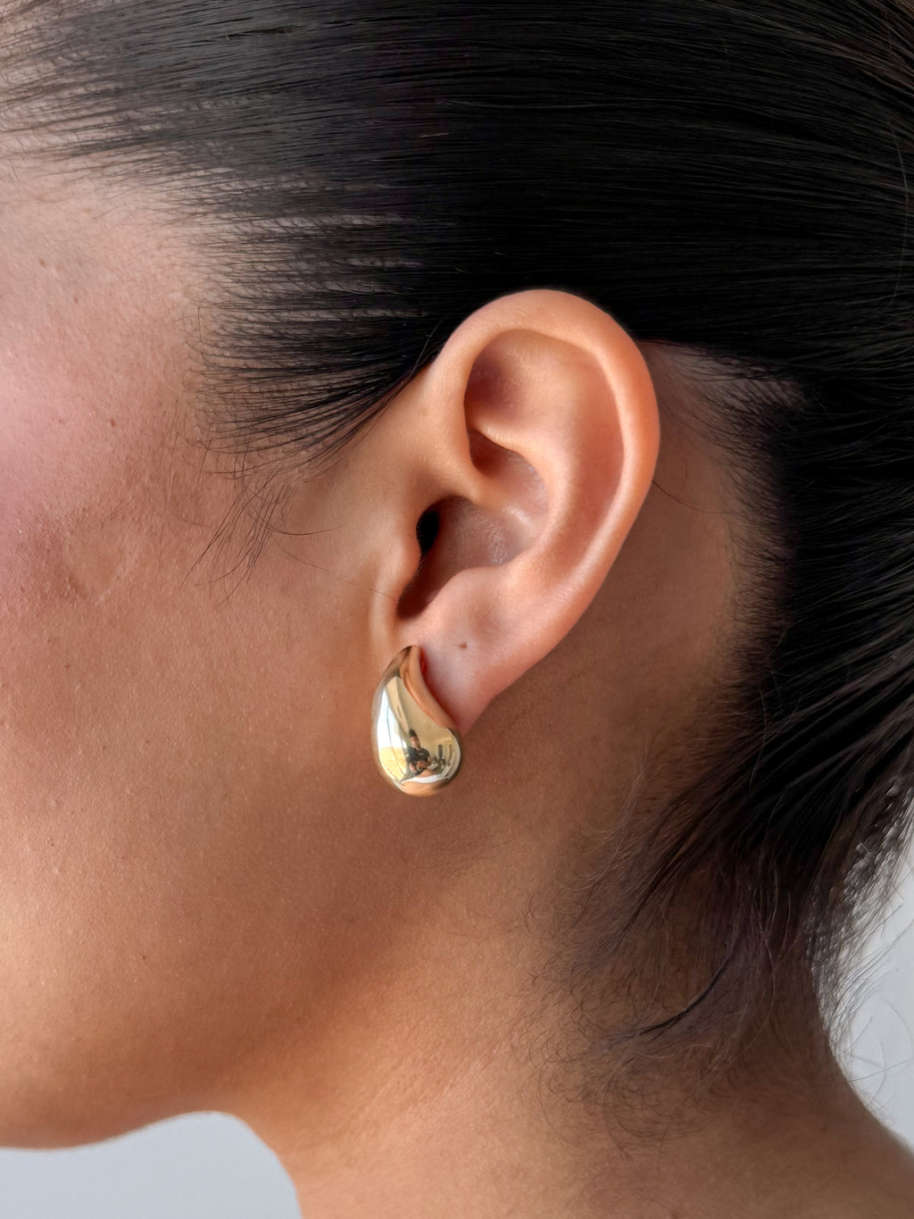 close-up of model wearing senoe gold teardrop stud earrings in 14k yellow gold